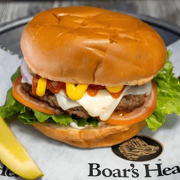 A juicy burger with melted cheese, lettuce, tomato, onion, ketchup, and mustard, served with a pickle.
